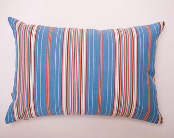 May include: A rectangular throw pillow featuring a vertical striped pattern in shades of light blue, white, red, yellow, and dark blue. The fabric has a visible woven texture, and the stripes vary in width across the entire surface of the pillow.