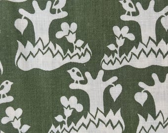 May include: A dark olive green fabric featuring a repeating white pattern of stylized trees, small birds perched on branches, heart-shaped leaves, and flowers emerging from jagged, mountain-like ground shapes across the textile surface.