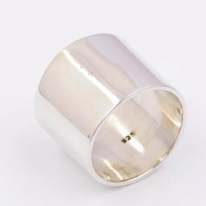 以下が含まれることがあります： 円筒形のデザインの、幅広で磨かれたシルバーリング。 リングは滑らかで反射する表面を持ち、内側には「925」の刻印があります。 このリングはおそらくスターリングシルバー製です。