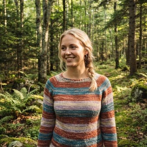Peut inclure: Un pull en tricot à manches longues avec un motif à rayures horizontales dans des tons variés d'orange rouille, bleu sarcelle, crème et violet doux. Le vêtement présente une encolure ronde, des manches raglan et des bords-côtes.