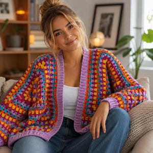 Peut inclure: Un gilet ouvert à manches longues arborant un motif au crochet de type granny square multicolore aux tons violet, orange, jaune et bleu, agrémenté d'une bordure côtelée violet clair unie sur le col, les poignets et l'ourlet.