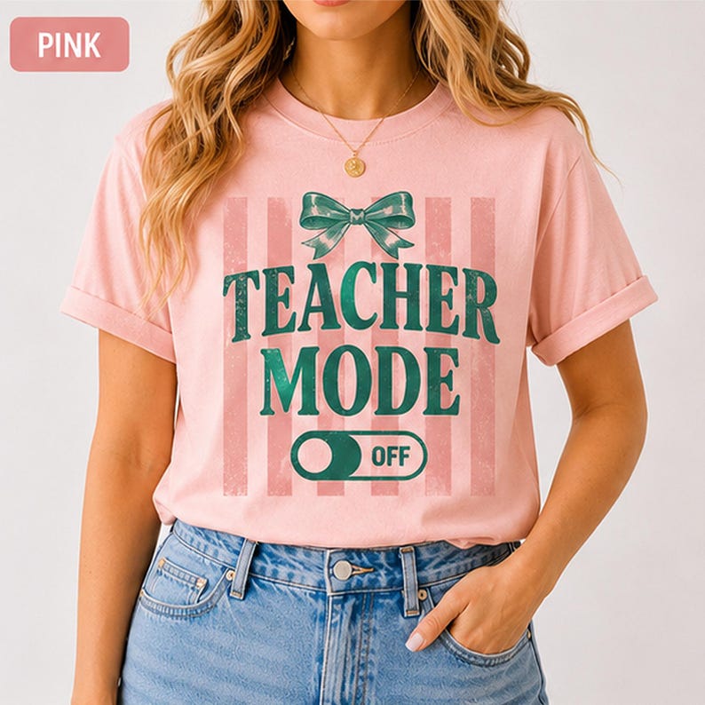 May include: Pink t-shirt with the text "TEACHER MODE OFF" in green, accented by a green bow and vertical stripes. The shirt is a light pink color and has short sleeves. The word "PINK" is in a pink box in the upper left corner.