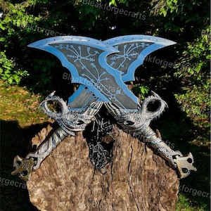 May include: Two crossed, ornate swords with blue blades and intricate silver handles. The blades feature etched designs and runes. The handles have dragon-like details and are set on a wooden surface.