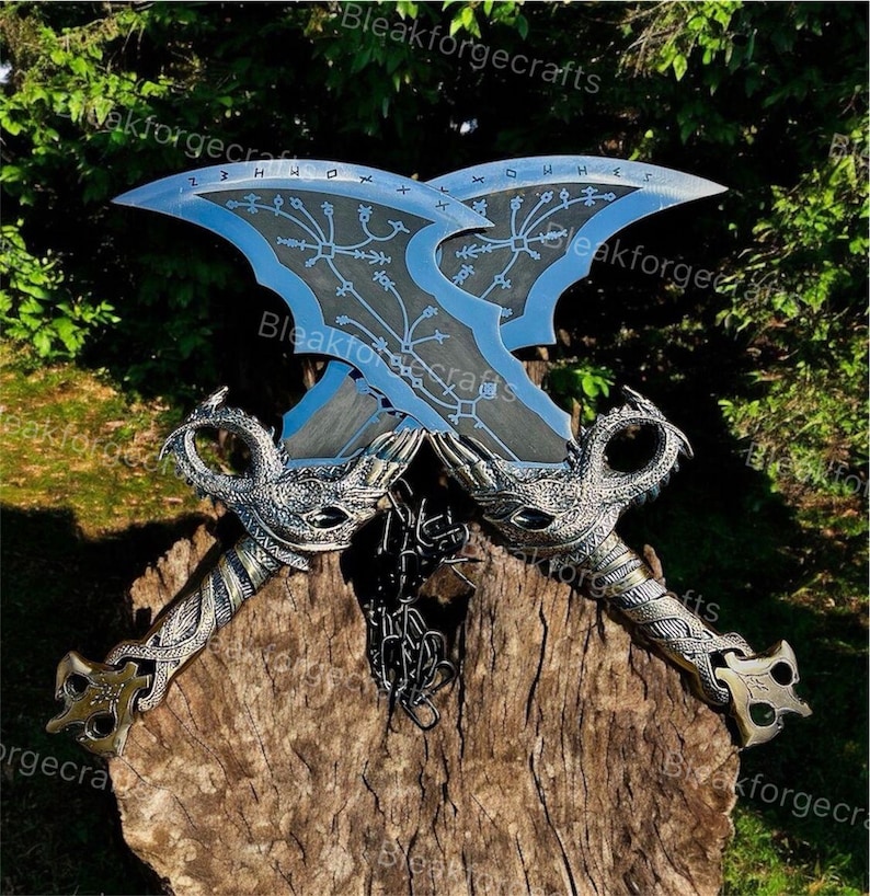 May include: Two crossed, ornate swords with blue blades and intricate silver handles. The blades feature etched designs and runes. The handles have dragon-like details and are set on a wooden surface.