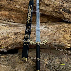 Puede incluir: Una espada plateada con empuñadura dorada y mango negro, junto a una vaina negra con detalles dorados. La espada tiene un diseño de ala estilizado en la empuñadura. La vaina tiene patrones decorativos dorados. El fondo es una superficie marrón texturizada.