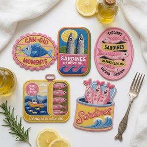 May include: Five embroidered patches featuring sardine themes. One is a scalloped oval with a blue fish and text CAN-DID MOMENTS. One is a rectangular tin with two fish and text SARDINES in olive oil. One is a pink oval with fish and text SARDINES IN PURE OLIVE OIL SMOKED ORIGINAL. One is a square tin with a boat and text QUITE THE CATCH! SARDINES in olive oil. One is a yellow tin with three pink fish and text Sardines.