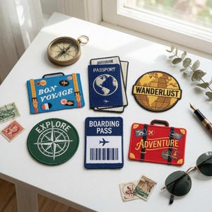 May include: A collection of embroidered travel-themed patches including a blue suitcase with Bon Voyage, a blue passport, a globe with Wanderlust, a green compass, a blue boarding pass, and a red suitcase with Adventure text, plus vintage stamps.