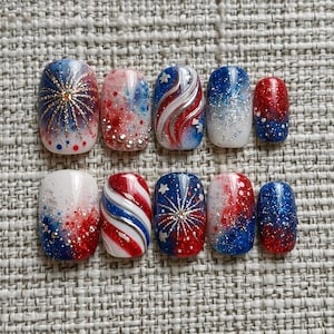 May include: A set of ten artificial nails with a patriotic theme. The nails feature designs in red, white, and blue, including glitter, fireworks, and star patterns. Some nails have a gradient effect, while others have stripes.