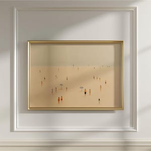May include: Framed art print showing a beach scene with many small figures on the sand. The artwork uses a muted palette of beige, tan, and light grey, with a gold-coloured frame. Some figures are wearing orange and black clothing.