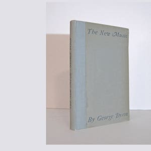 May include: A light blue book with the title "The New Music" and the author "By George Dyson" printed on the cover.