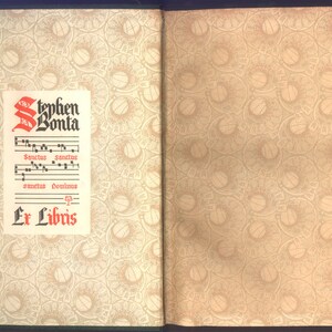 May include: Open book with decorative patterned pages. The left page features a printed label with the name "Stephen Bonta" in red and black, along with musical notation and the words "Ex Libris". The right page has a circular pattern.