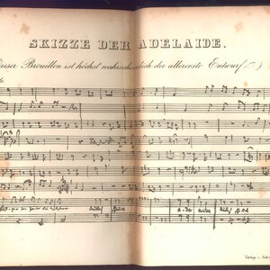 May include: Open book with aged, yellowed pages featuring handwritten musical notation. The title "SKIZZE DER ADELAIDE" is visible at the top. The text is in German. The book's spine is dark green.