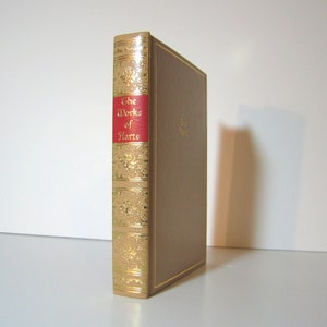 May include: A tan-colored book with gold accents and a red spine. The spine reads "The Works of Harte".