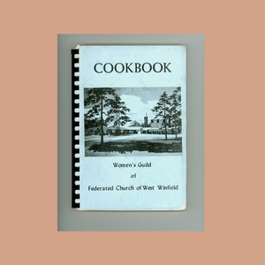 Puede incluir: Un libro de cocina azul con el título "Cookbook" en texto negro. La portada presenta una ilustración en blanco y negro de un edificio de iglesia con árboles en primer plano. El texto debajo de la ilustración dice "Women's Guild of Federated Church of West Winfield."