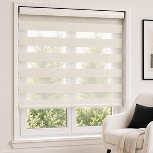 Pu&ograve; includere: Una tenda a rullo a doppio strato con bande orizzontali alternate di tessuto solido color bianco sporco e materiale a rete trasparente. La tenda &egrave; montata all'interno di un telaio bianco, lasciando filtrare la luce attraverso le sezioni.
