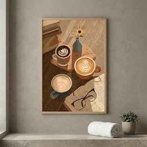 May include: A framed print featuring a cozy coffee scene. Three mugs of latte art sit on a wooden surface, alongside an open book with glasses, a small vase with a sunflower, and a stack of books. The color palette is warm and inviting.