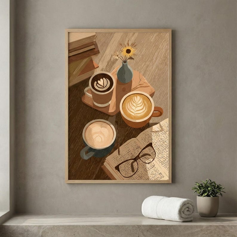 May include: A framed print featuring a cozy coffee scene. Three mugs of latte art sit on a wooden surface, alongside an open book with glasses, a small vase with a sunflower, and a stack of books. The color palette is warm and inviting.
