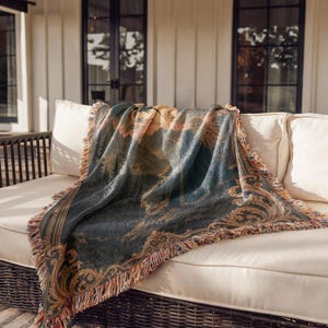 Woven tapestry blanket with a fantasy scene of a woman in a blue cloak looking at a mountain landscape.