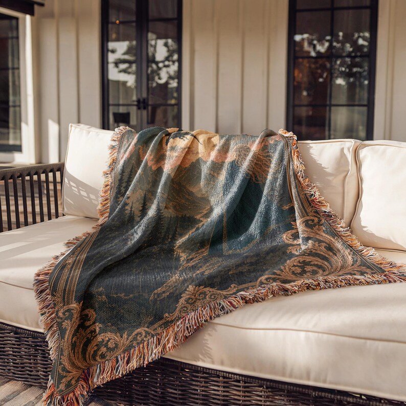 Woven tapestry blanket with a fantasy scene of a woman in a blue cloak looking at a mountain landscape.