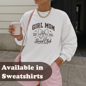 White sweatshirt with "Girl Mom Social Club" graphic and pink striped shorts.