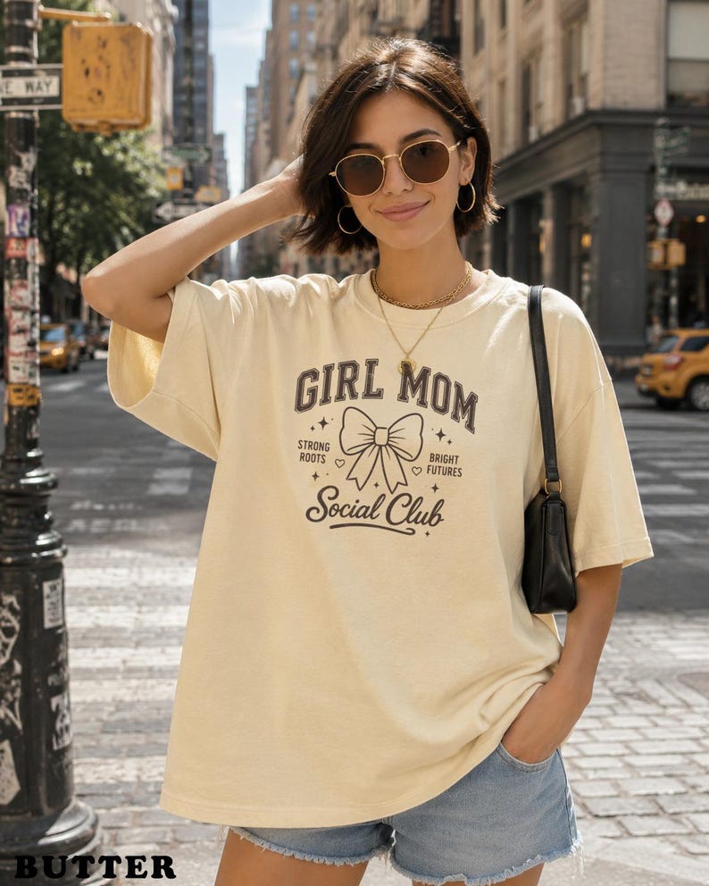Cream t-shirt with "Girl Mom" text and bow graphic.