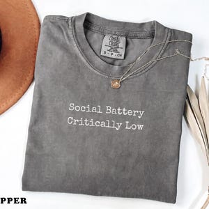 Comfort Colors Pepper t-shirt with "Social Battery Critically Low" text.