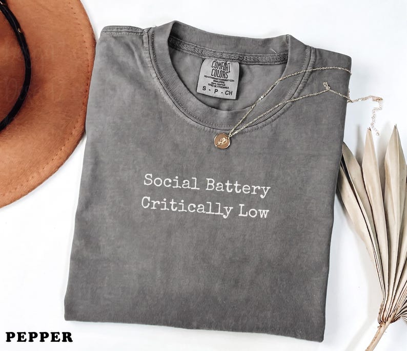 Comfort Colors Pepper t-shirt with "Social Battery Critically Low" text.