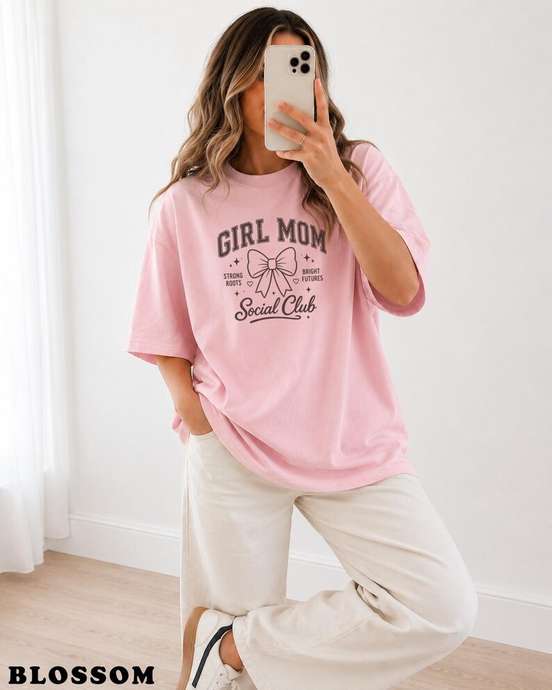 Pink t-shirt with "Girl Mom Social Club" graphic, worn by a woman.