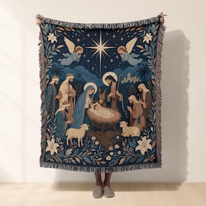 Könnte beinhalten: Eine gewebte Wohndecke mit einer dunkelblauen Krippenszene, einem zentralen Stern, Engeln, der heiligen Familie, den heiligen drei Königen und Tieren. Das Design ist von floralen Motiven umrahmt und hat Fransen an der Ober- und Unterseite.