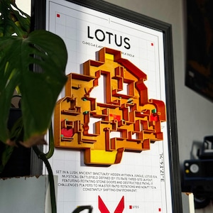 Op de afbeelding: Ingelijste kunstwerk met een 3D-kaart van het "Lotus" slagveld, in geel en rood. De kaart staat tegen een witte rasterachtergrond, met de tekst "Lotus" en "Omega Earth". Het kunstwerk zit in een zwarte lijst.