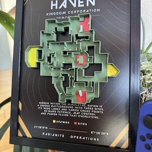 Op de afbeelding: Een ingelijste 3D-kaart van het Haven-slagveld uit Valorant, met een groene plattegrond en rode en gele accenten. De tekst luidt Haven Kingdom Corporation, met coördinaten 27°28'0"N 87°38'30"E en Radianite Operations.