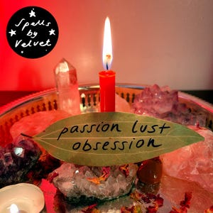 Könnte beinhalten: Eine rote Kerze mit brennender Flamme steht auf einem silbernen Tablett, umgeben von verschiedenen Kristallen wie Bergkristall und Amethyst. Ein getrocknetes Lorbeerblatt mit dem handgeschriebenen Text 'passion lust obsession' liegt davor.