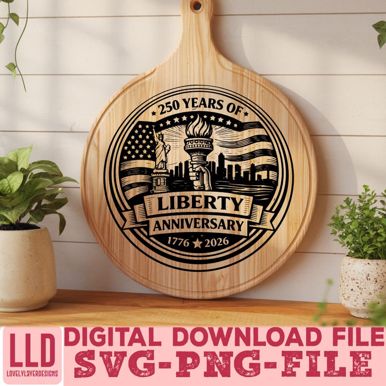 May include: A round wooden cutting board with a handle, featuring a black graphic commemorating the Liberty Anniversary. The design includes the Statue of Liberty, a waving American flag, and the text "250 Years of Liberty Anniversary 1776-2026".