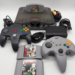 Può includere: Una console Nintendo 64 color antracite traslucido con una cartuccia di Super Mario 64 inserita, un controller nero, un controller grigio Under Control, un alimentatore, cavi e due cartucce di gioco aggiuntive: International Superstar Soccer 98 e Virtual Pool 64.