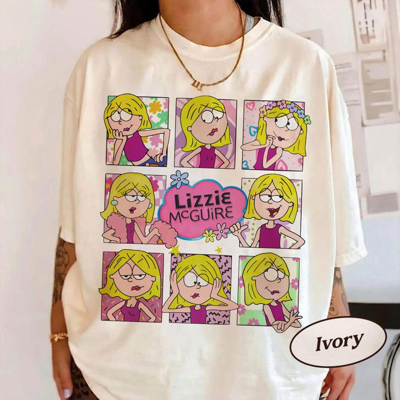 May include: Ivory-colored t-shirt featuring a grid of Lizzie McGuire cartoon images. The images show Lizzie in various poses, with the show's logo in a pink cloud. The shirt is a casual wear item.