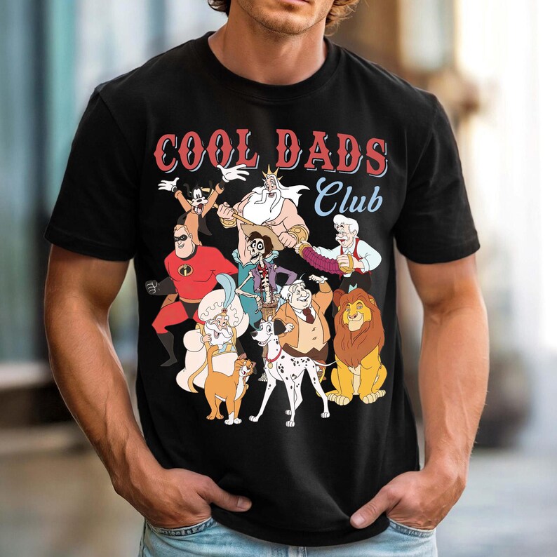 K&ouml;nnte beinhalten: Schwarzes T-Shirt mit einer Grafik von Zeichentrickfiguren und dem Text "COOL DADS Club" in Rot und Wei&szlig;. Das Design zeigt Figuren wie Micky Maus, Mr. Incredible und Scar.