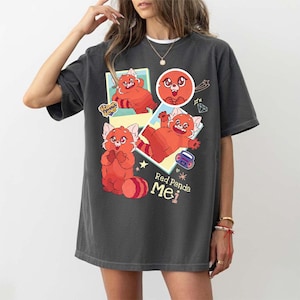 Può includere: T-shirt grigio scuro con un design a cartone animato di panda rosso. La grafica include il testo "Red Panda Mei" e altre illustrazioni. La maglietta ha un girocollo e maniche corte.