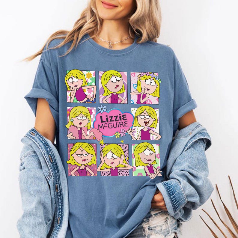 May include: Blue t-shirt featuring a graphic of Lizzie McGuire in various poses. The graphic includes the text "Lizzie McGuire" in a pink cloud with flowers. The shirt is a light blue color.