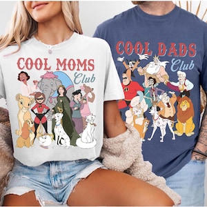 Puede incluir: Dos camisetas, una blanca y otra azul marino, con personajes de dibujos animados. La camiseta blanca dice "COOL MOMS CLUB" y la camiseta azul marino dice "COOL DADS CLUB". Ambas camisetas tienen varios personajes de dibujos animados.