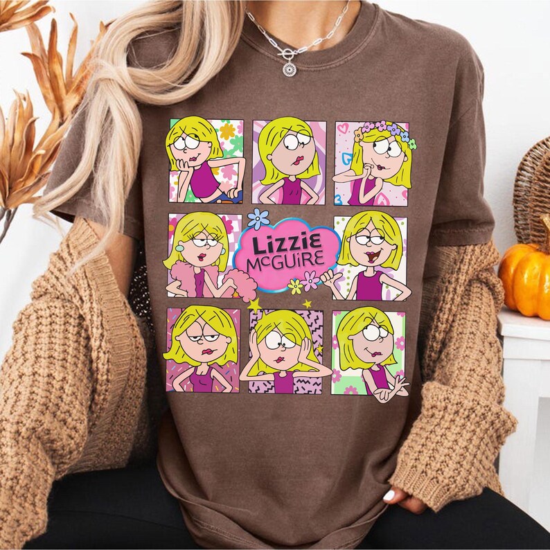 May include: Brown t-shirt featuring a grid of nine images of a cartoon character with blonde hair and a pink outfit. The text "Lizzie McGuire" is in a pink cloud. The shirt has short sleeves.