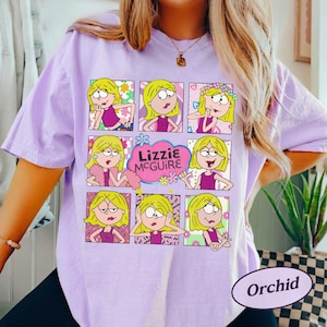 May include: Orchid-colored t-shirt featuring a grid of cartoon images of a blonde girl in various poses. The text "Lizzie McGuire" is in a pink cloud. The shirt has short sleeves.