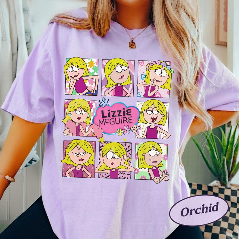 May include: Orchid-colored t-shirt featuring a grid of cartoon images of a blonde girl in various poses. The text "Lizzie McGuire" is in a pink cloud. The shirt has short sleeves.