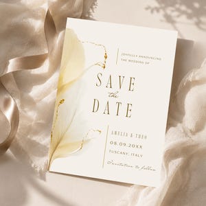 May include: A cream-colored Save the Date card featuring a delicate yellow floral illustration with gold accents. The text reads: Joyfully announcing the wedding of, Save the Date, Amelia & Theo, 08.09.20XX, Tuscany, Italy, Invitation to follow.