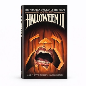 Pu&ograve; includere: Copertina del libro "Halloween II" con una zucca intagliata con la bocca aperta e i denti. Il titolo &egrave; in lettere bianche in grassetto su sfondo nero. Il testo "THE #1 SCREEN SHOCKER OF THE YEAR!" &egrave; sopra il titolo.
