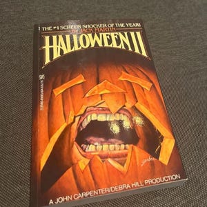 Pu&ograve; includere: Un libro tascabile intitolato "Halloween II" di Jack Martin. La copertina presenta una zucca intagliata con la bocca aperta e i denti. Il libro &egrave; una produzione di John Carpenter/Debra Hill.