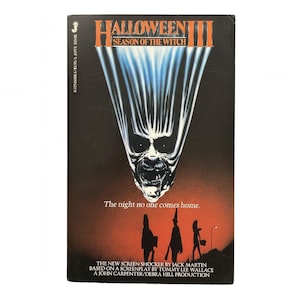 May include: A vintage VHS tape for "Halloween III: Season of the Witch." The cover features a menacing skull-like face with a white and blue light effect against a dark background. Text includes the title, tagline, and production credits.