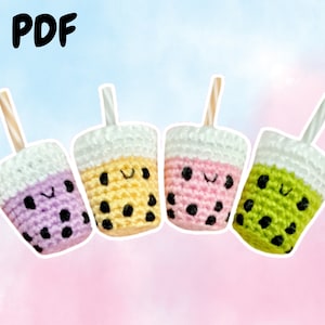 May include: Four crocheted boba tea cups with smiling faces. The cups are purple, yellow, pink, and green. Each cup has a straw.