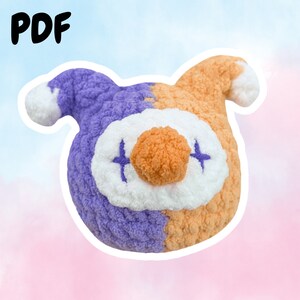 Peut inclure: Un jouet en peluche crocheté en forme de bouffon avec un schéma de couleurs violet et orange. Le jouet a un visage blanc avec un petit nez en pompon orange et des yeux brodés.