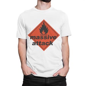 May include: White t-shirt featuring a red diamond with a black flame graphic and the words "massive attack" in black. The shirt is a crew neck style.