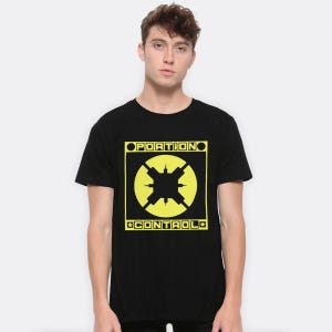 以下が含まれることがあります： 黒いTシャツ。黄色の長方形のボックスに「PORTION CONTROL」と書かれた黄色のグラフィック。グラフィックには、十字型のデザインの黄色い円が含まれています。Tシャツはクルーネックで半袖です。